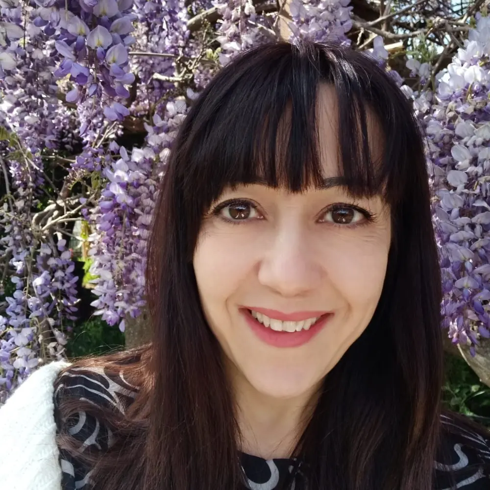 Cinzia Cerbino, fondatrice di Sii Re Academy, ritratta davanti a un glicine in fiore