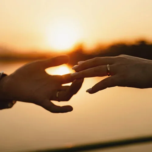 Due mani che si avvicinano al tramonto, simbolo di sostegno e accompagnamento